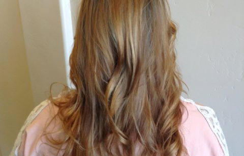 Long light brown hair with golden ends in soft curls, back view