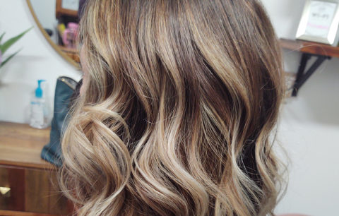 Dark-rooted blonde waves with bright ends, back view